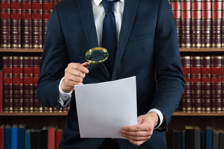 Attorney reviewing legal documents with a magnifying glass